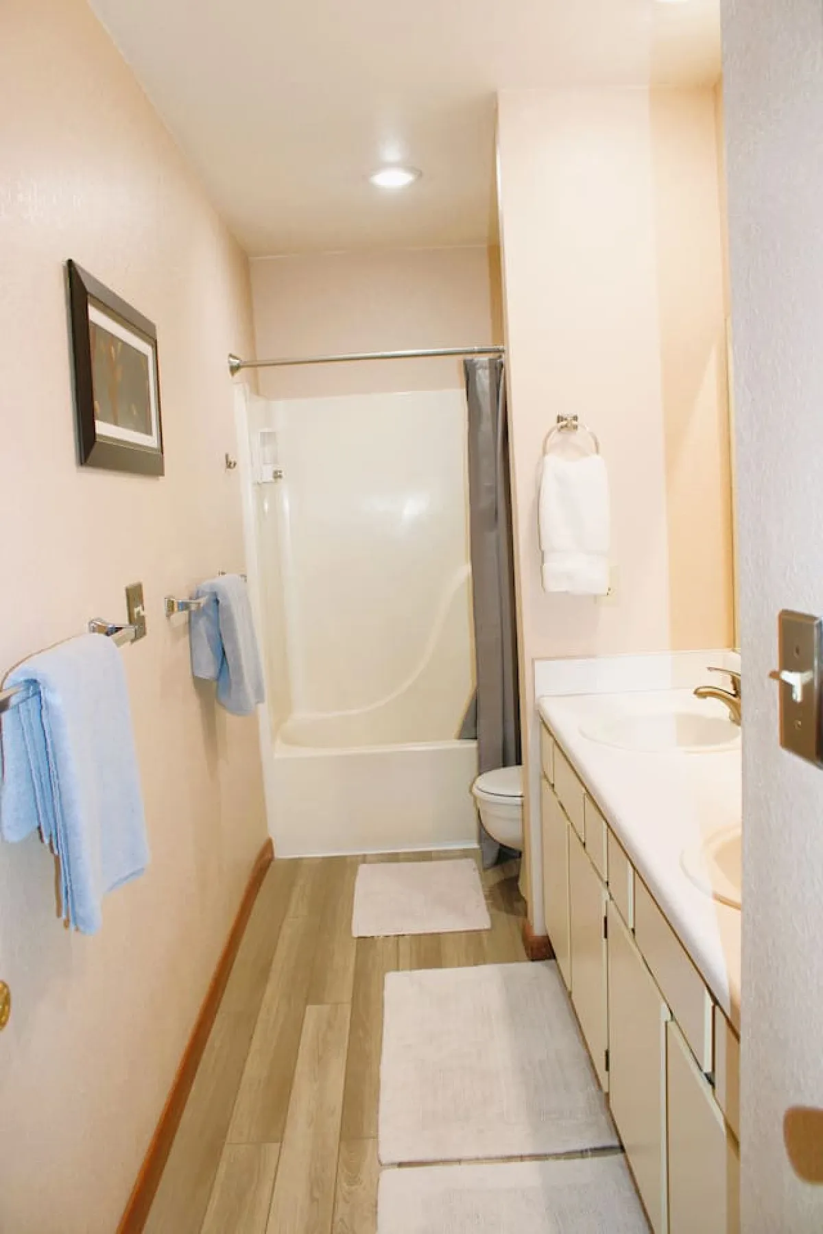 A modern bathroom featuring a double sink vanity, a relaxing bathtub, crisp towels, and a framed picture. The design is clean and contemporary, with ample space and thoughtful details supporting easy routines and relaxation.