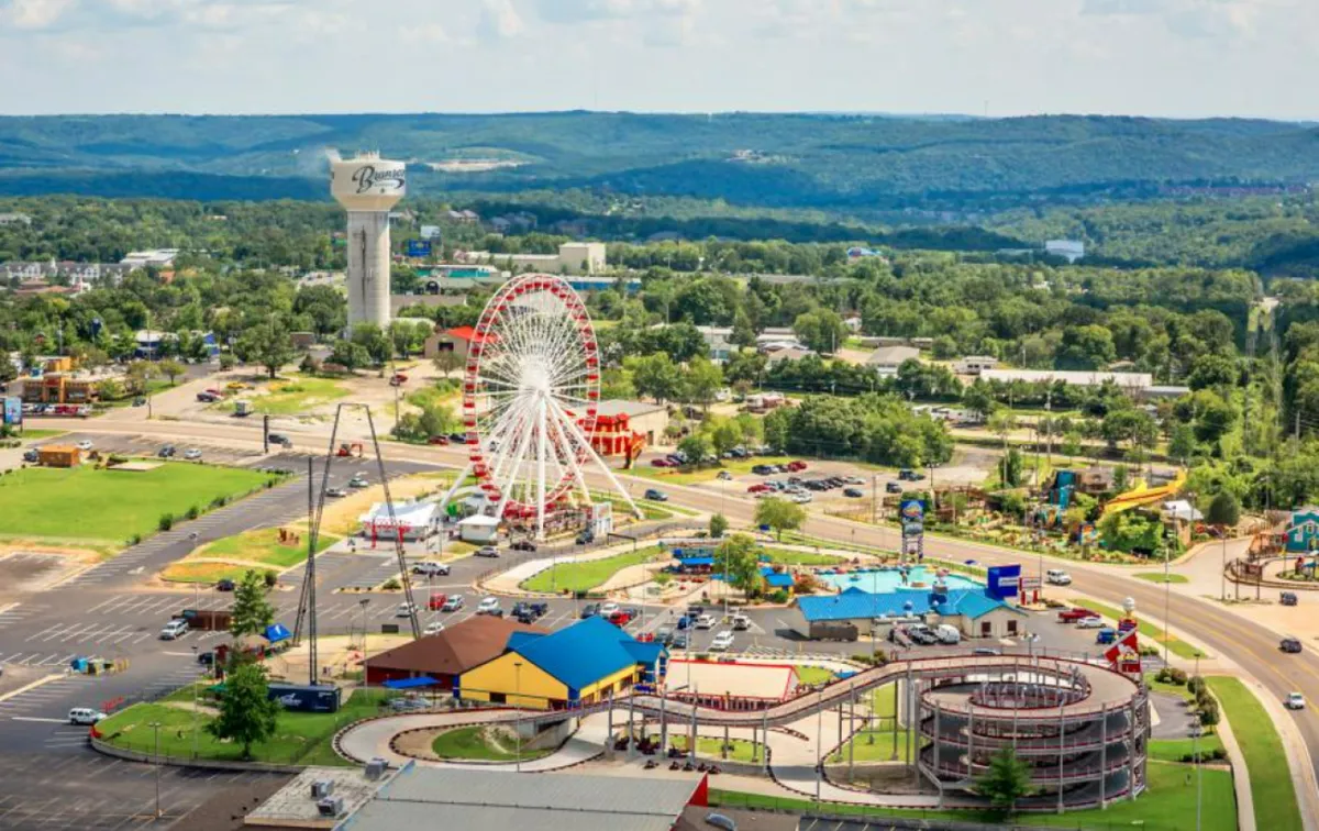 A lively shot of an amusement park with a ferris wheel, bright rides, colorful buildings, and lush green landscape. Families and children are visible enjoying the park, evoking feelings of joy and togetherness.