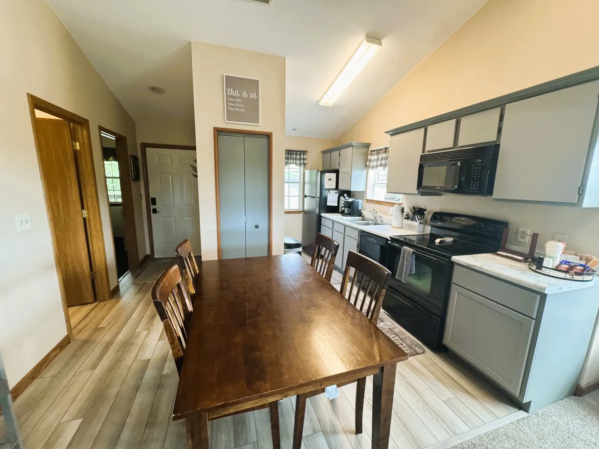 A cozy interior highlighting a dining table set for a meal, with kitchen appliances visible in the background. A window with curtains adds a touch of homeliness. The scene conveys a sense of readiness for celebrations, casual family recipes, or hosting friends for dinner.